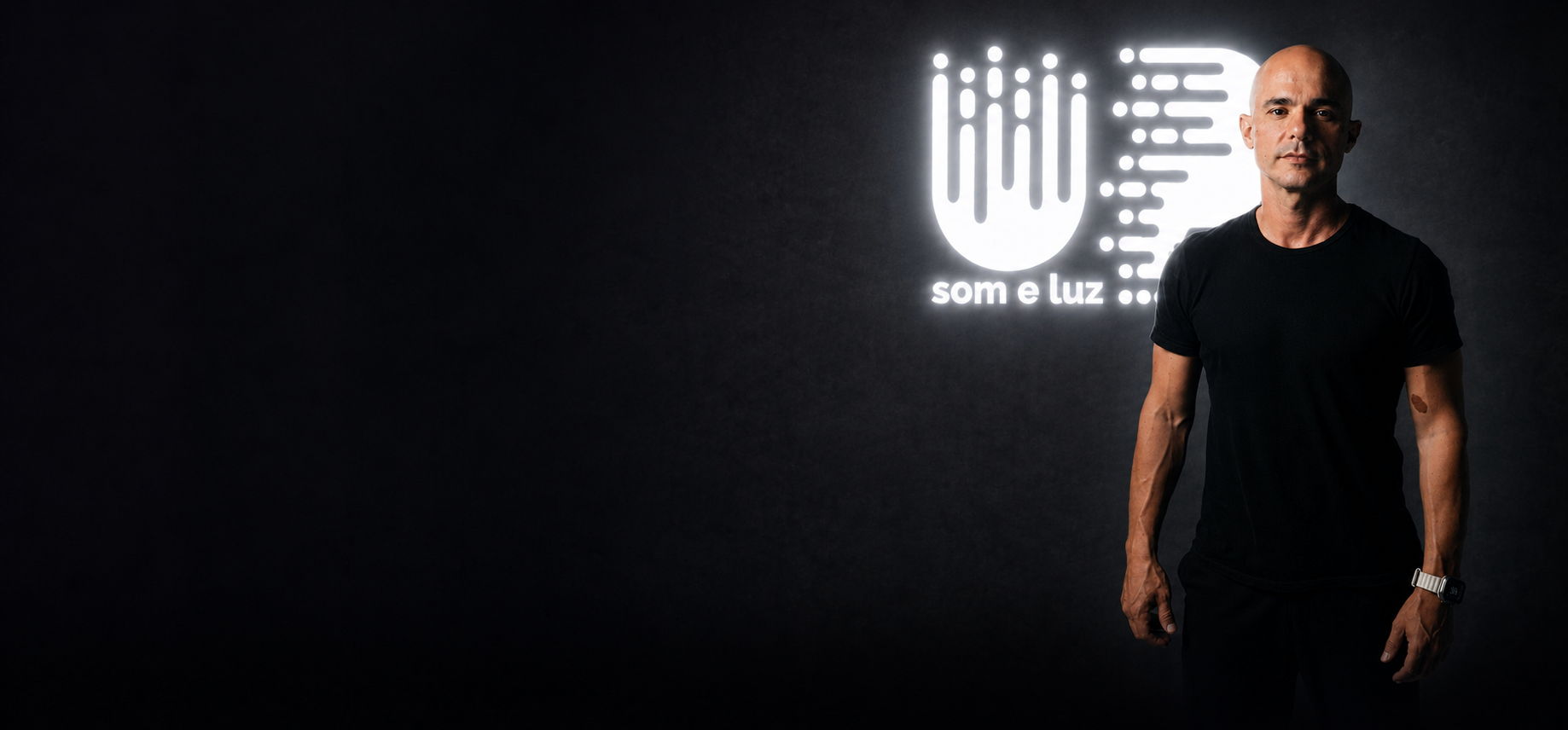 Bernardo, fundador, e Luciana, sócia, diante do logo iluminado da UP Som e Luz